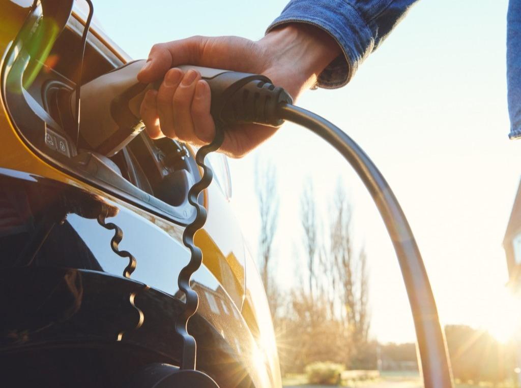 Person using an EV charger to charge an electric car