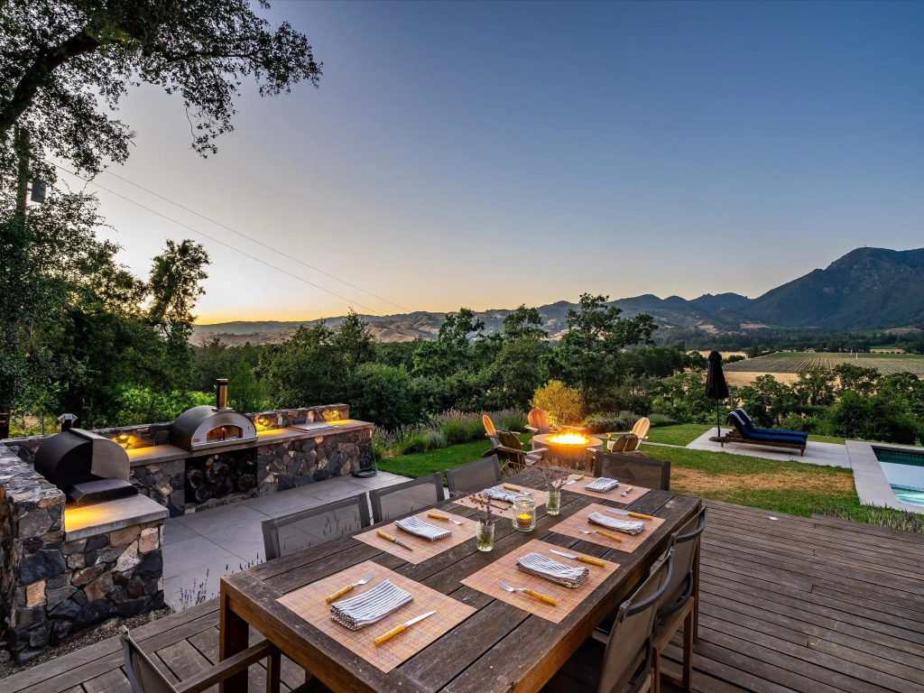 Table setting outside on wooden deck with mountains and hills in the background during sunset